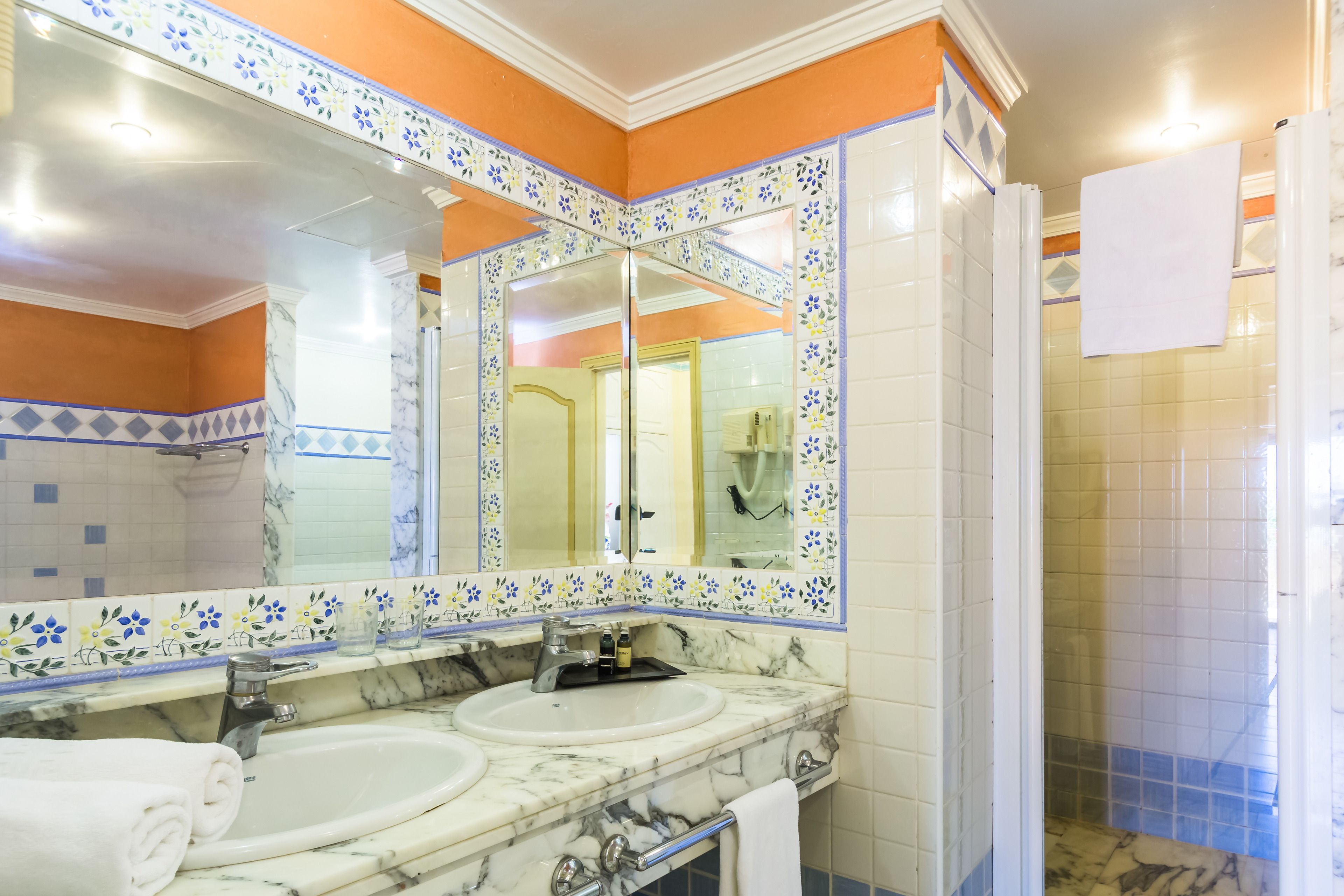 Une salle de bain avec deux lavabos, un grand miroir et un espace douche.