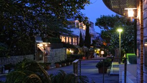 A courtyard with stone walls, potted plants, and a well-lit pathway. - Hotel Le Pinarello (Zonza)