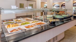 Buffet com diversos alimentos e uma vitrine de vidro.