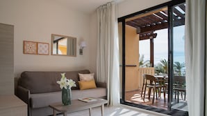 Uma sala de estar moderna com um sofá, mesa de centro e vista para um pátio externo com cadeiras e uma mesa.