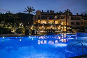 A swimming pool with a reflection of a building and palm trees.