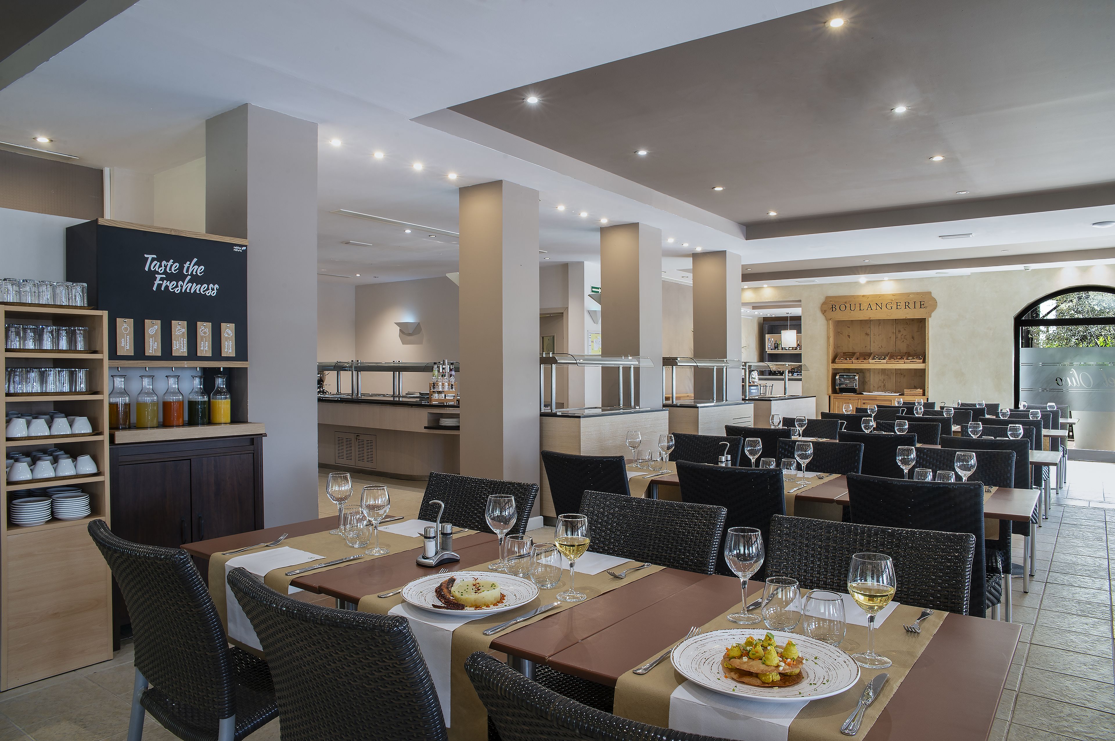 En restaurant med flere spiseborde og stole, et barområde samt et udvalg af drikkevarer.
