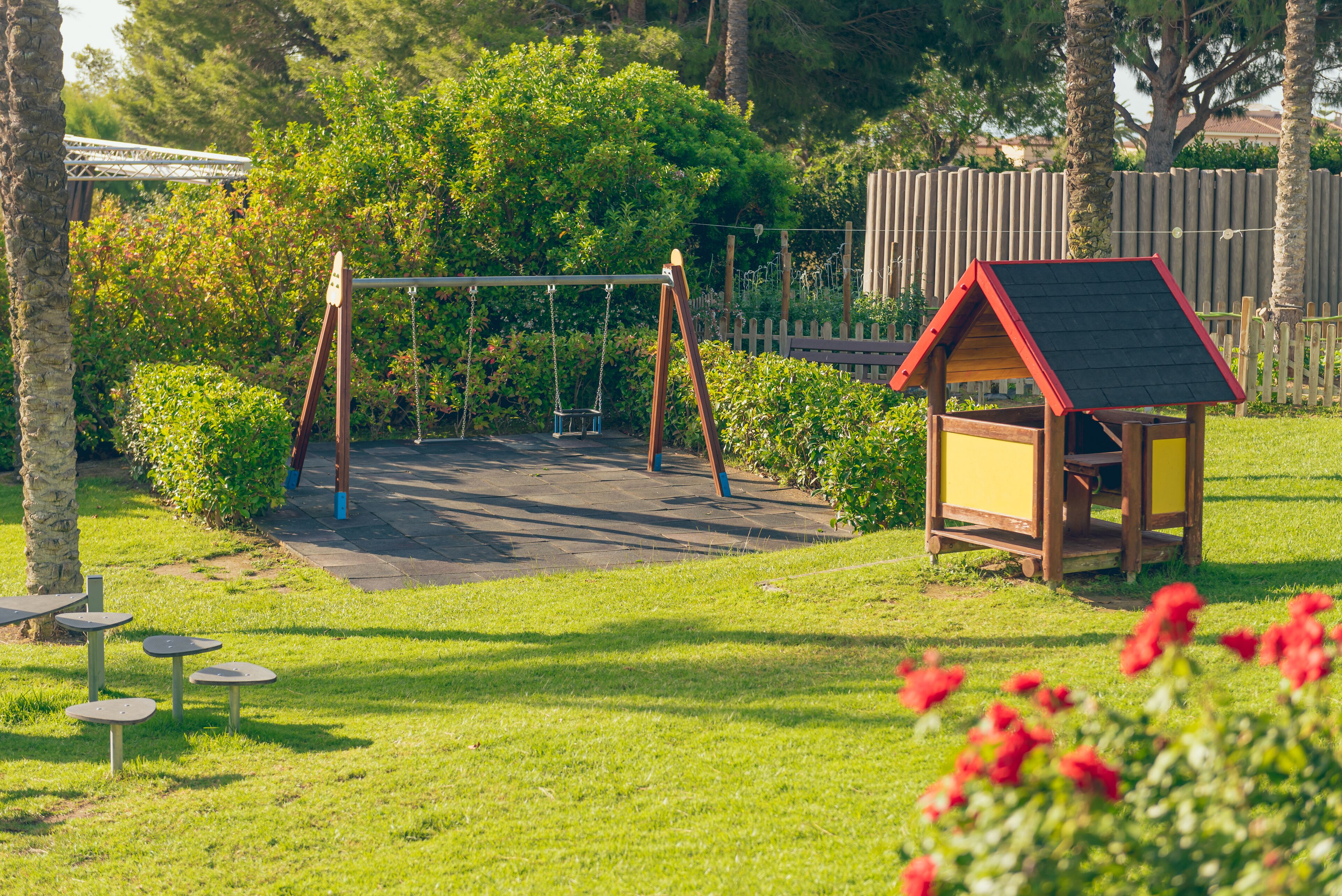 A playground with swings and a small wooden structure.
