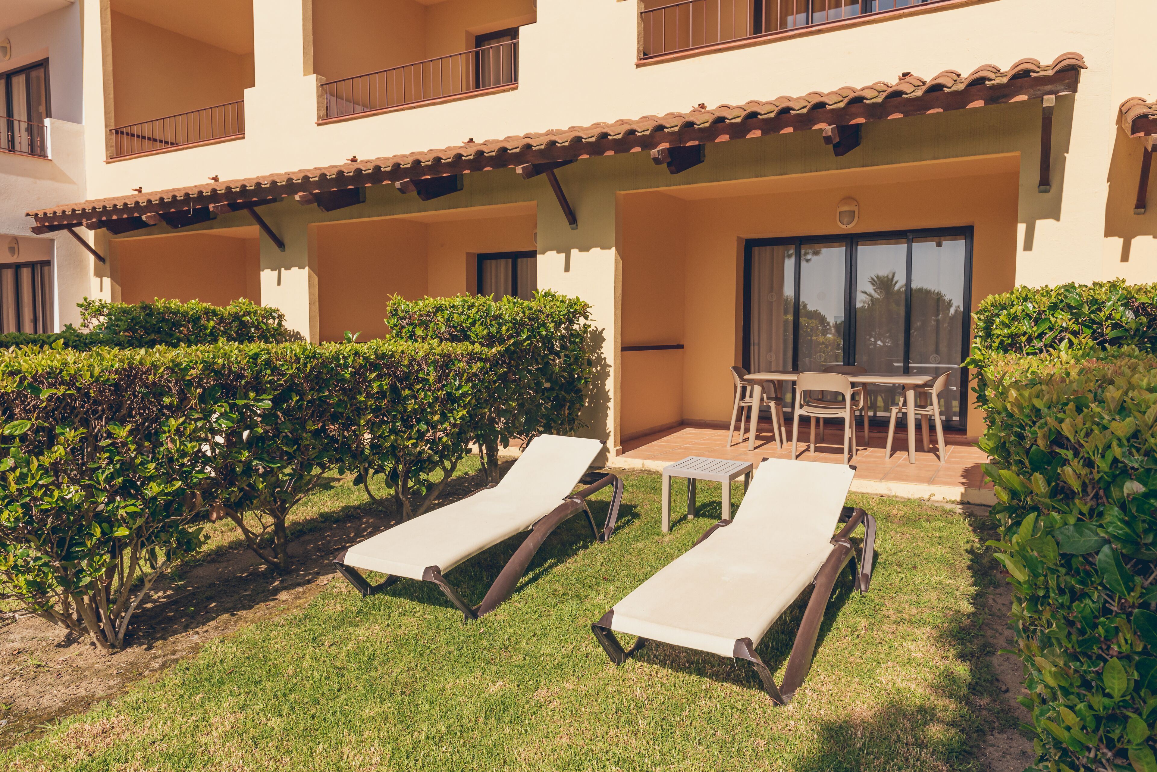 A courtyard with two lounge chairs, a small table, and a chair.