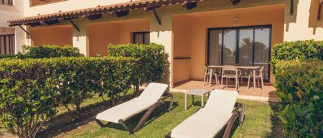 A courtyard with two lounge chairs, a small table, and a chair.