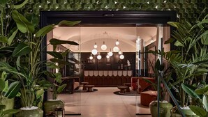 A modern lobby with large potted plants, a seating area with sofas and a coffee table, and a chandelier. - Falkensteiner Hotel Prague (Prague)