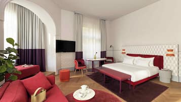 Moderni hotellihuone, jossa on suuri sänky, sohva, työpöytä ja televisio.