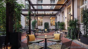 A courtyard with outdoor seating, potted plants, and a central table with candles. - Falkensteiner Hotel Prague (Prague)