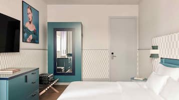 A hotel room with a bed, a dresser, a mirror, a television, and a door.