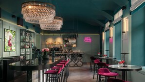 A bar area with a long counter, multiple bar stools, and a chandelier. - Falkensteiner Hotel Prague (Prague)