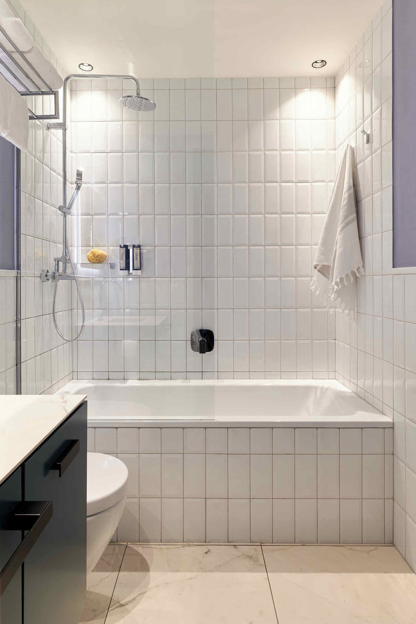 A modern bathroom with a bathtub, toilet, and shower.