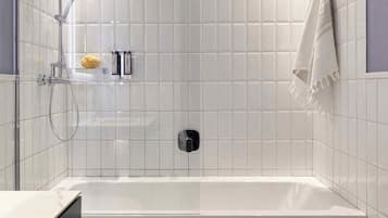 A modern bathroom with a bathtub, toilet, and shower.
