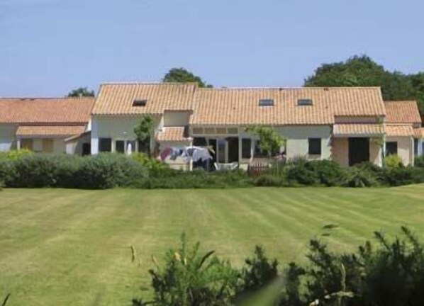 Un bâtiment à deux étages, doté d’un toit en tuiles, entouré de pelouses et d’arbustes bien entretenus.