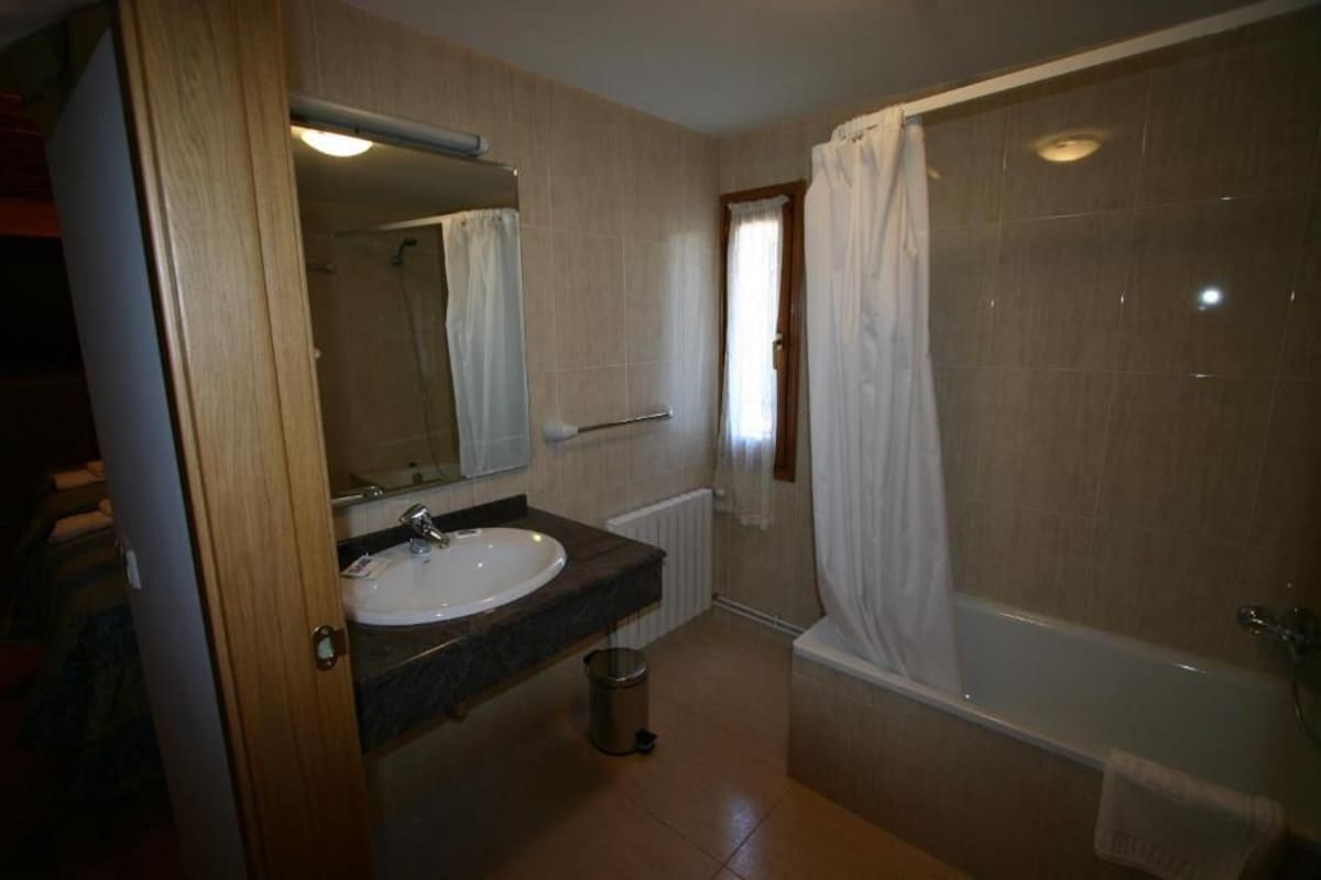 Une salle de bain équipée d’un lavabo, d’un miroir, d’une douche et d’un porte-serviettes.