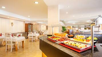 A buffet area with various food items, tables, and chairs arranged for dining.