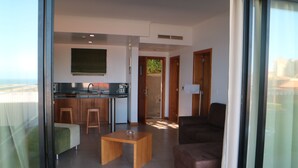 A modern living room with a sofa, a coffee table, and a kitchen area with a sink and stools.