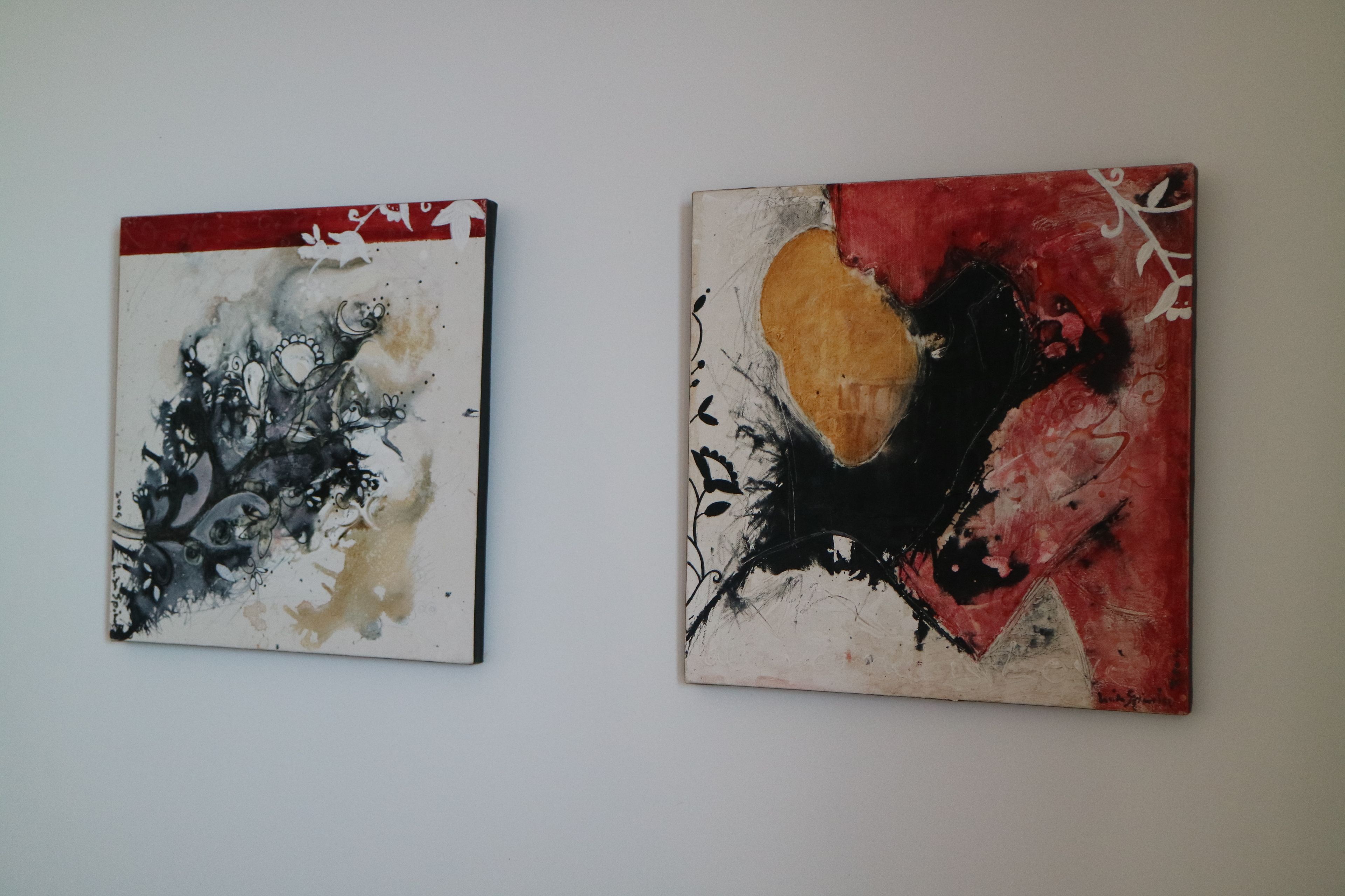Two abstract paintings on a plain wall.
