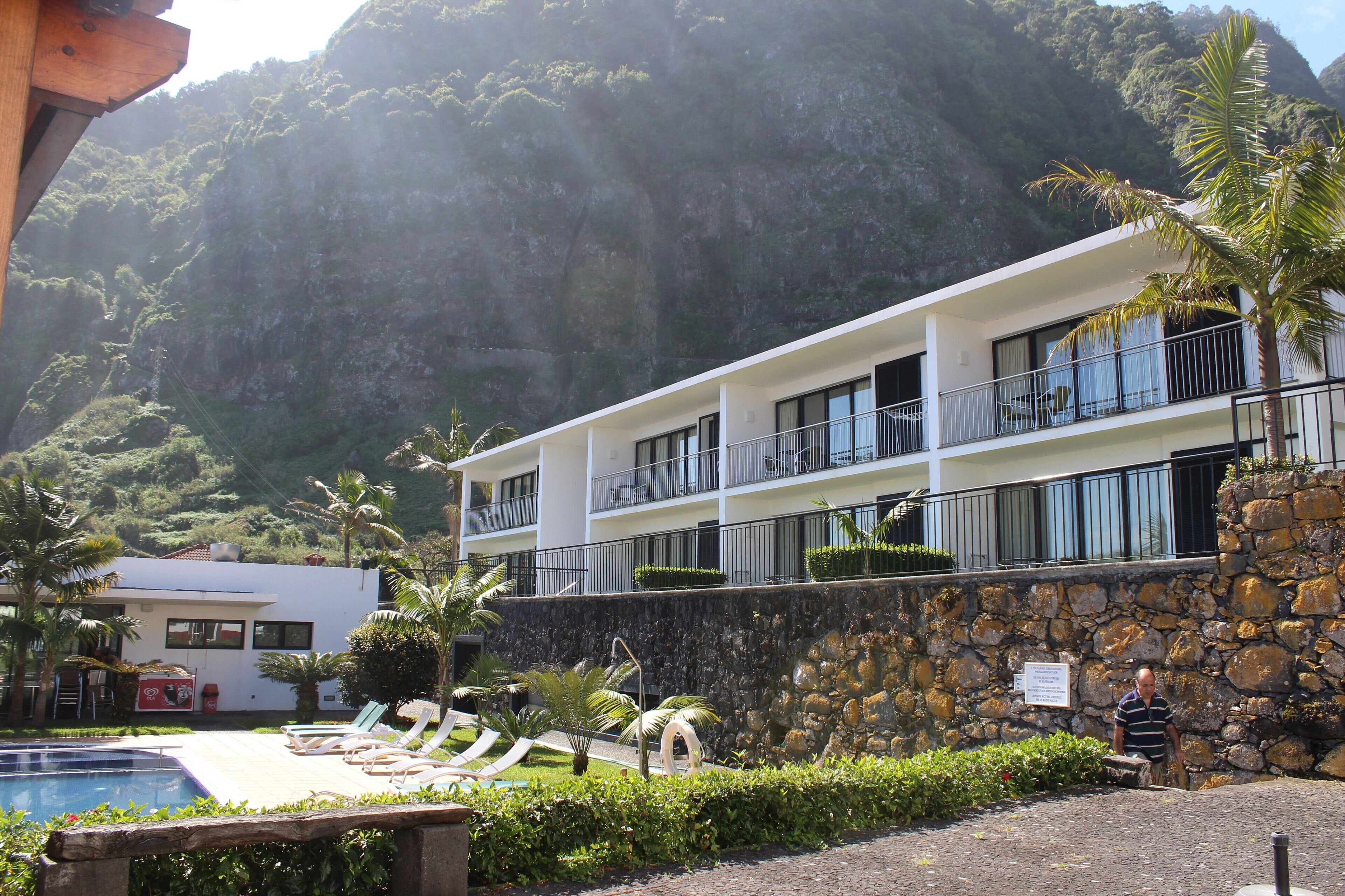 Un hôtel doté d’une piscine, de chaises longues et offrant une vue sur un paysage montagneux.