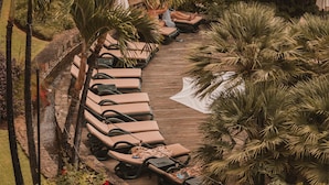 A resort with a wooden deck, lounge chairs, and tropical plants. - Royal Savoy - Ocean Resort - Savoy Signature (Funchal)