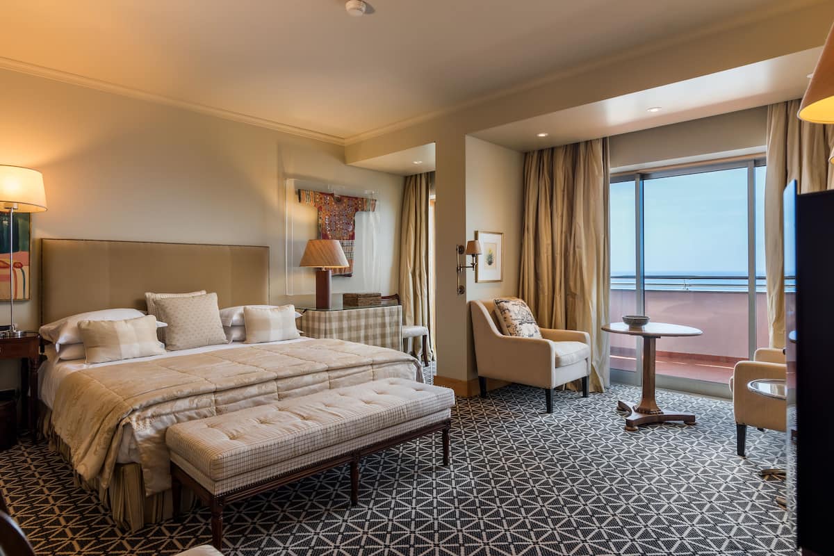 Een hotelkamer met een groot bed, een zithoek met een tafel en uitzicht op buiten.