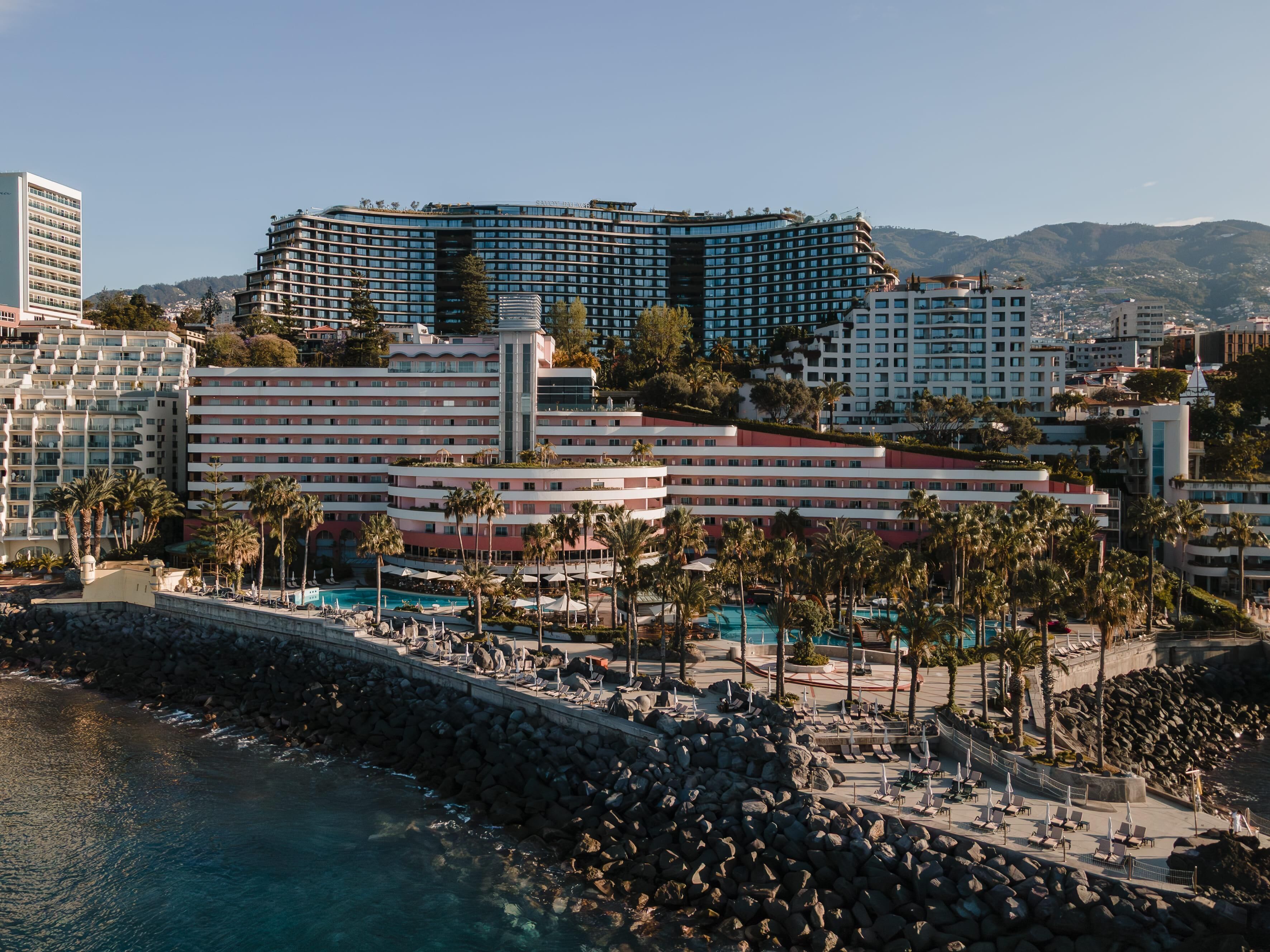 Un hôtel situé sur la côte, composé de plusieurs bâtiments, doté d’un espace piscine et bordé d’une plage rocheuse.