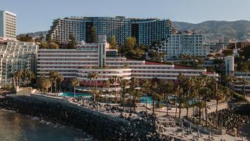 Un hôtel situé sur la côte, composé de plusieurs bâtiments, doté d’un espace piscine et bordé d’une plage rocheuse.