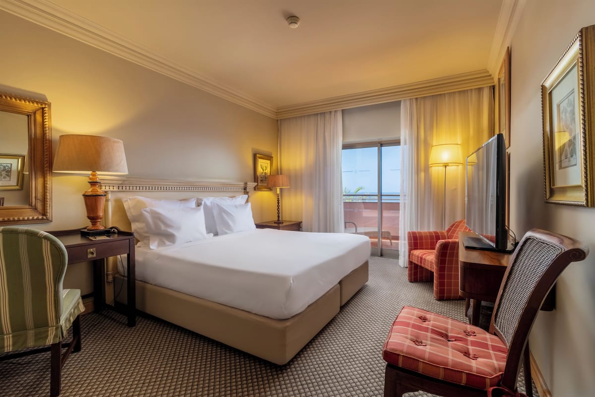 Een hotelkamer met een groot bed, een bureau, een stoel en een televisie.