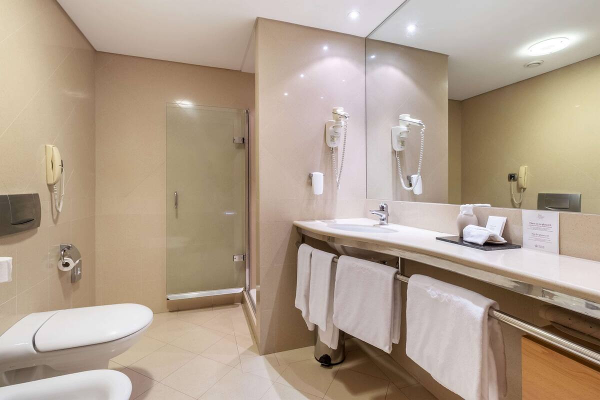 Een moderne badkamer met toilet, wastafel en douche.