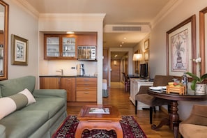 A living room with a green sofa, a wooden coffee table, and a dining area with a table set for two.