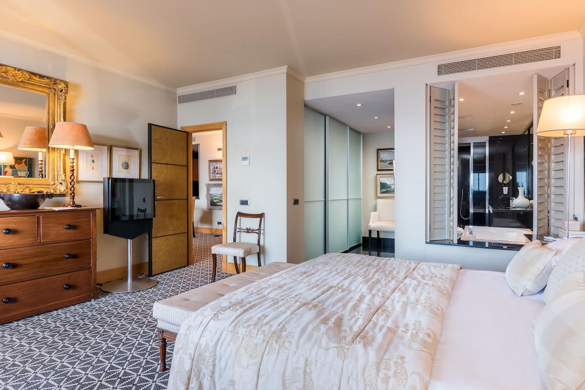 Een hotelkamer met een bed, dressoir, televisie en een grote spiegel.
