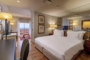 A hotel room with a large bed, bedside lamps, a desk, a chair, and a TV.