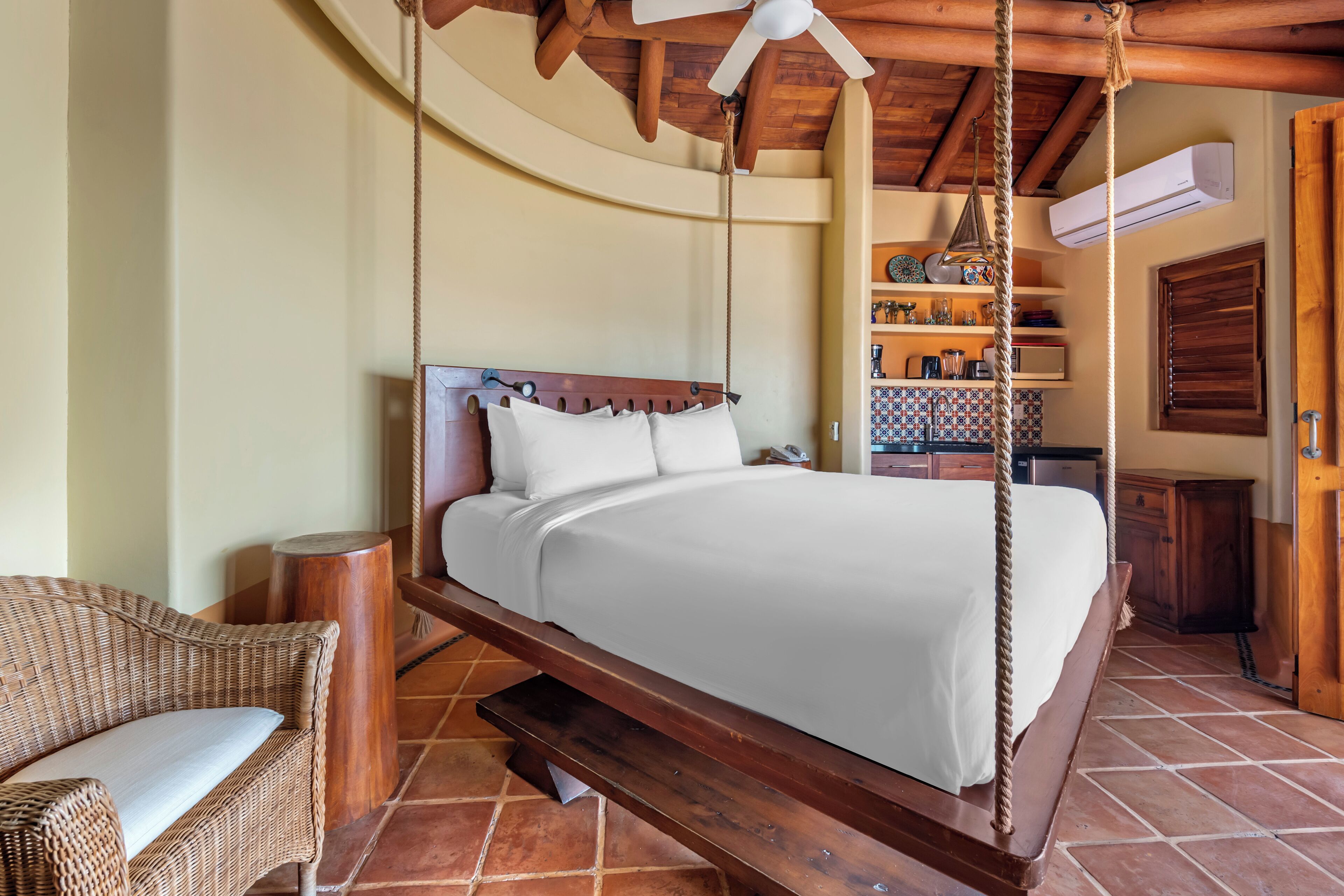 A spacious bedroom with a large bed, wooden headboard, and a hanging swing chair.
