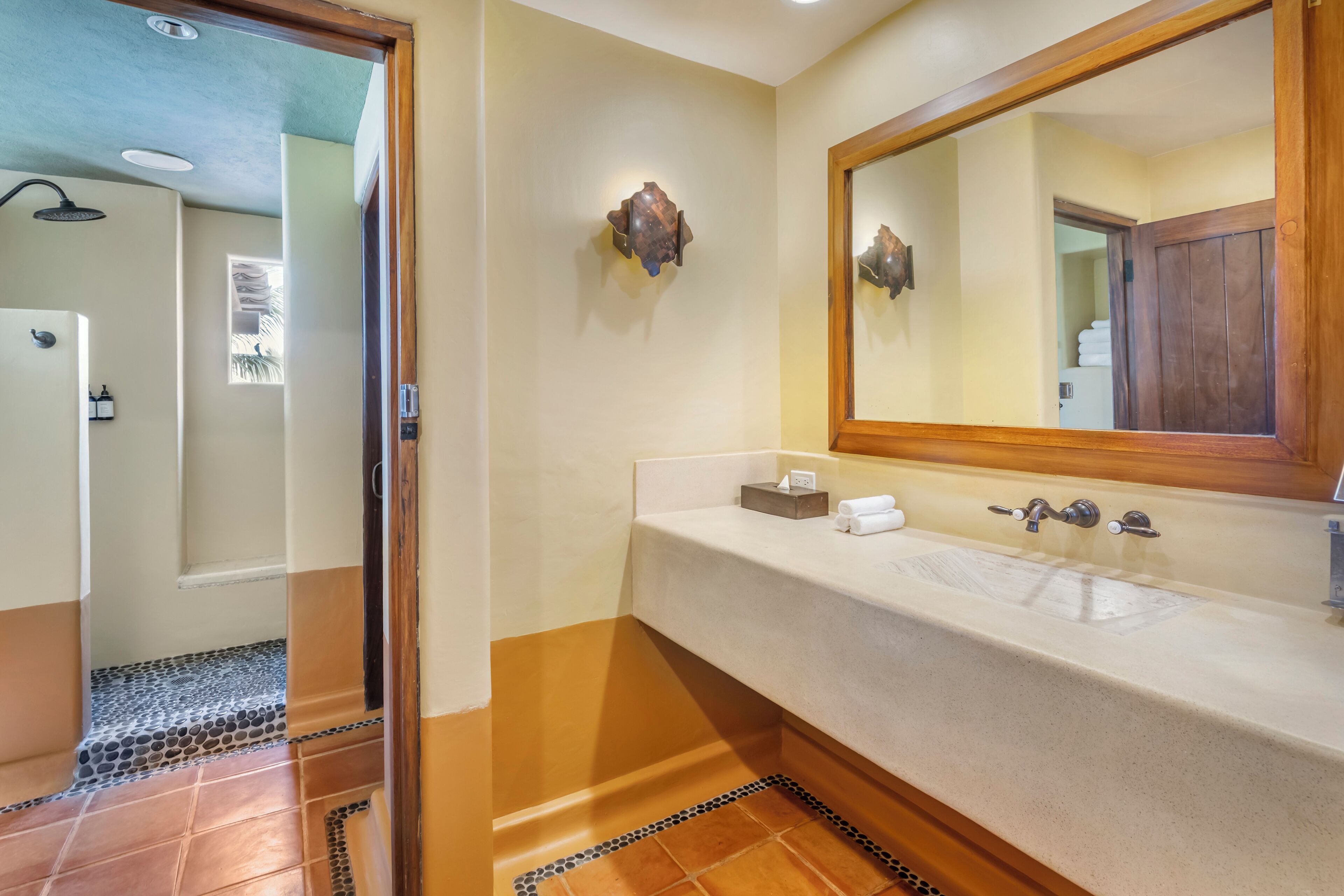 A bathroom with a large mirror, a sink with a towel holder, and a shower area.