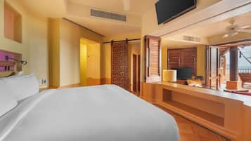 Habitación de hotel con una cama grande, televisión, escritorio con silla y balcón con vistas.