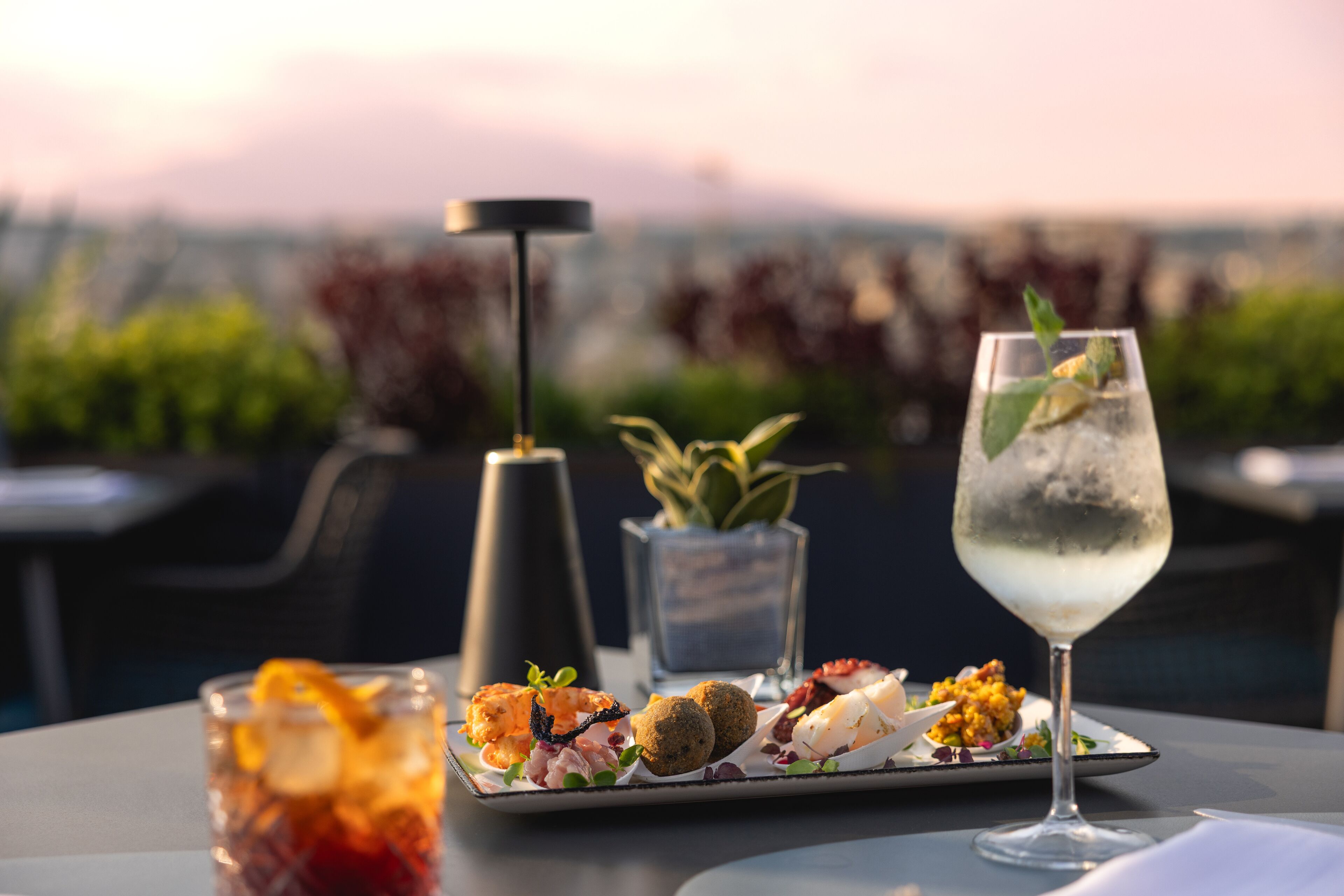 A table with a variety of appetizers, a glass of white wine, and a candle.
