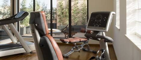 Un gimnasio con equipo de ejercicio, ventanas amplias y vistas al exterior.