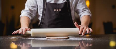 A person rolling dough on a reflective countertop.