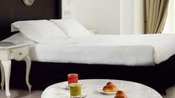 A hotel room with a bed, a bedside table, a round marble table with food, and a wall with a decorative plate.