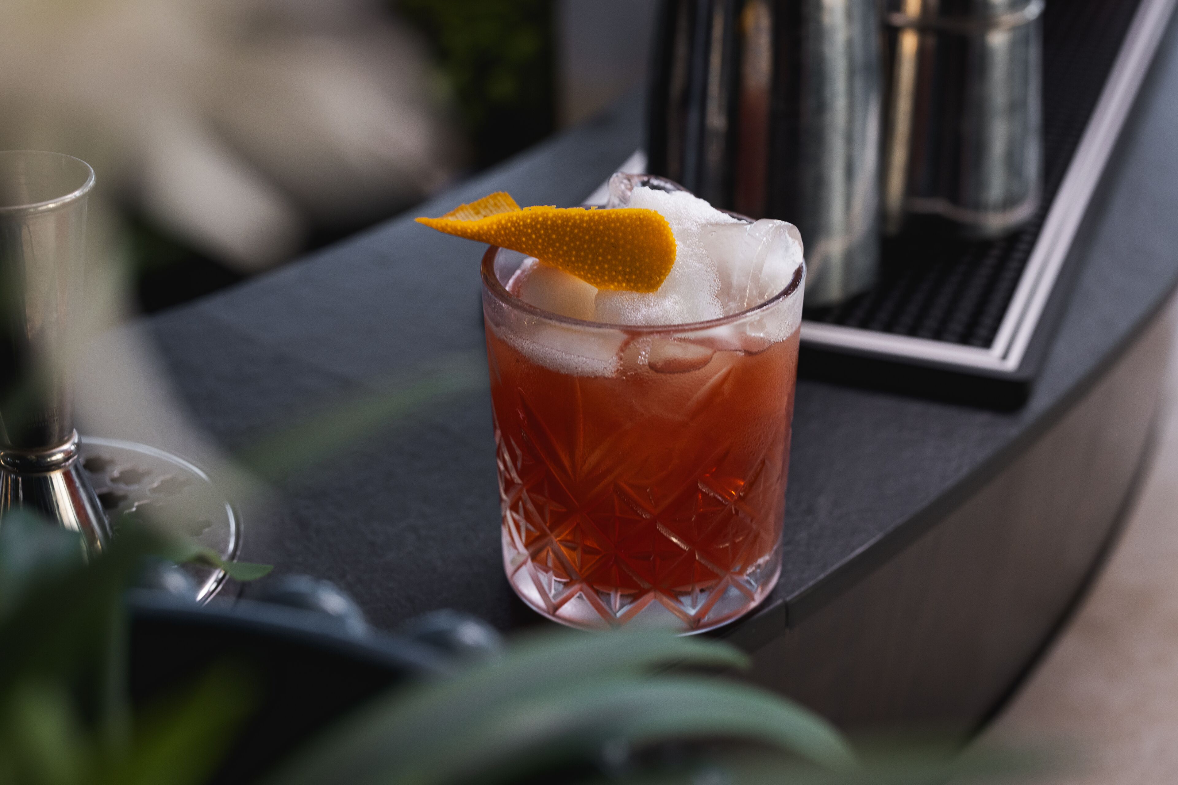 A cocktail glass with a lemon twist garnish on a bar counter.