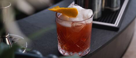 A cocktail glass with a lemon twist garnish on a bar counter.
