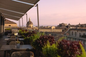 A terrace with outdoor seating, a view of historic buildings, and a dome structure in the distance. - Palace Catania | UNA Esperienze (Catania)