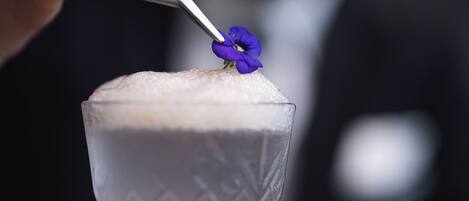 A cocktail with a flower garnish in a glass.