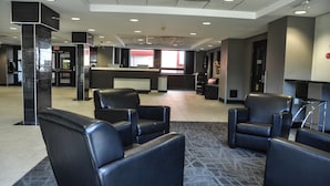 A lobby with black leather chairs, a reception desk, and a patterned carpet. - Residence & Conference Centre - Oakville (Oakville)