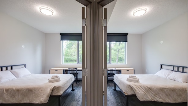 A hotel room with two beds, a desk, and a chair. - Residence & Conference Centre - Oakville (Oakville)