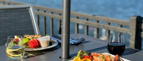 A table with a meal, a drink, and a view of the sea.