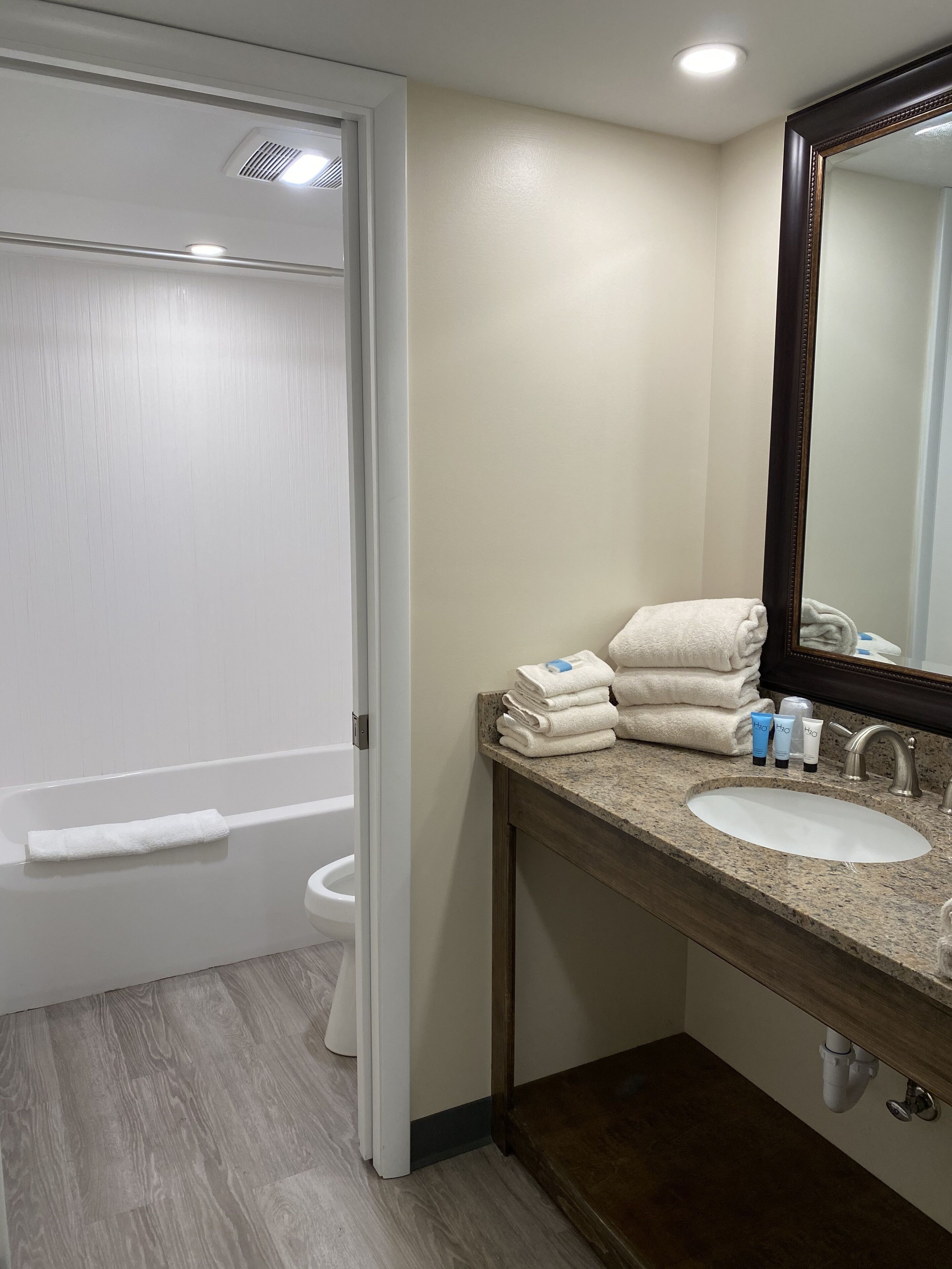 A bathroom with a white bathtub, a sink with toiletries, and a mirror.