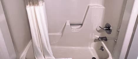 A modern bathroom with a bathtub, a shower, and a toilet.