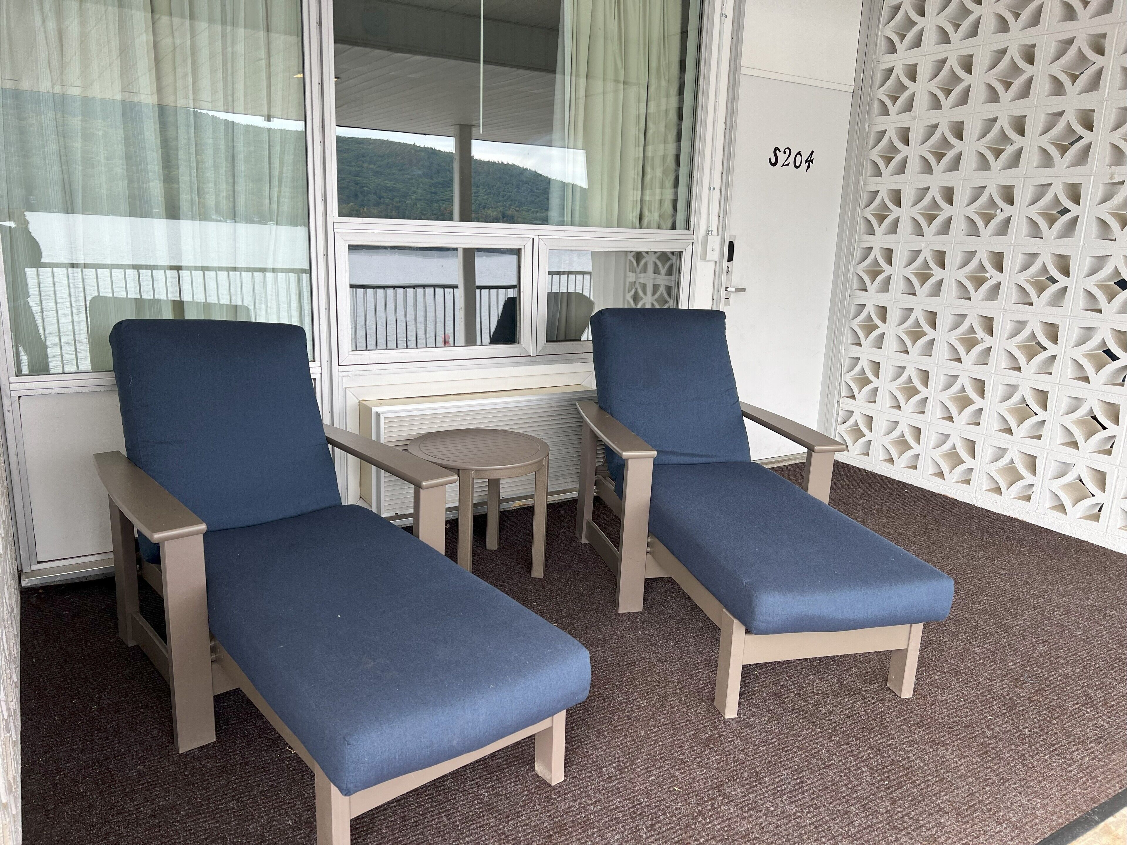 A room with two blue lounge chairs, a small round table, and a white partition with a geometric pattern.