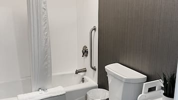 Un baño moderno con ducha, inodoro y un estante pequeño con artículos de aseo.