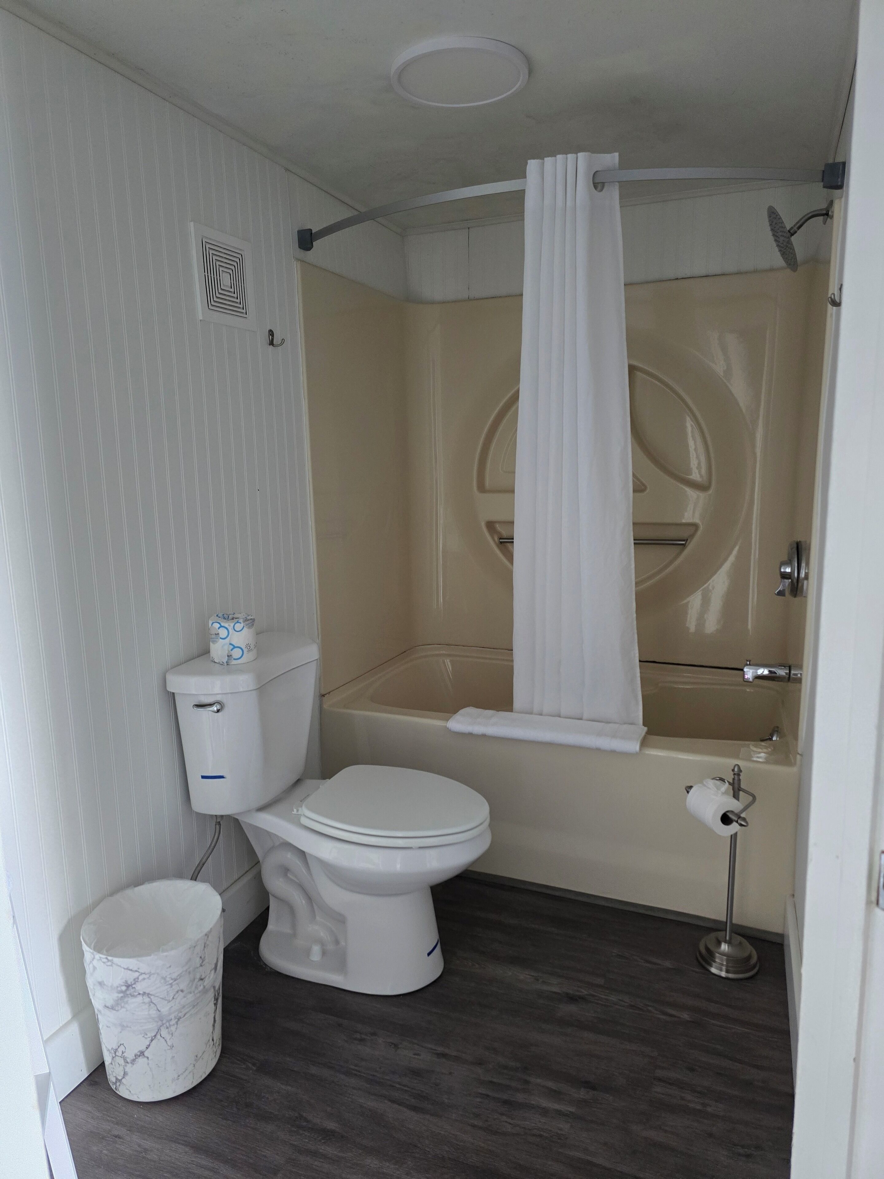 A compact bathroom with a toilet, a bathtub, and a shower curtain.